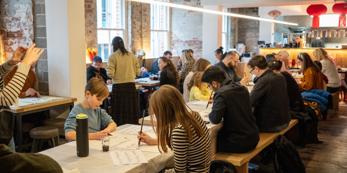 Rows of tables filled with people who are drawing and painting.