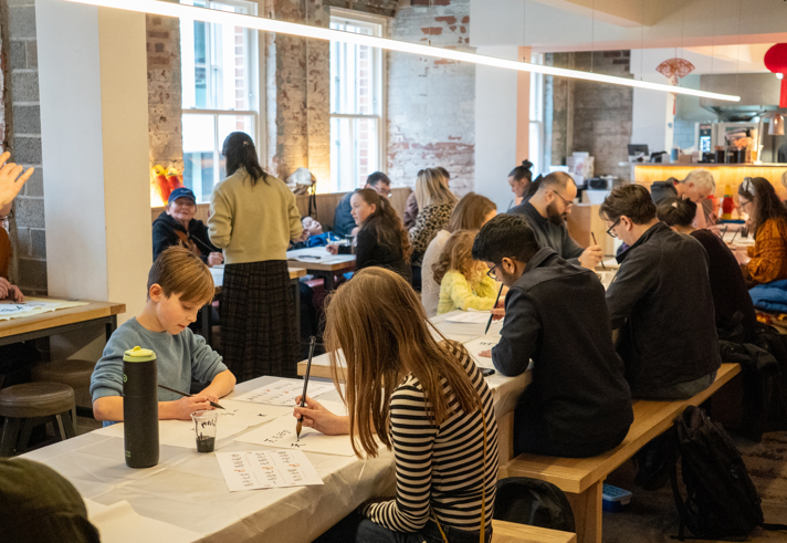 Rows of tables filled with people who are drawing and painting.