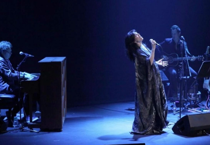 Imelda May performing live on stage in subdued blue lighting.