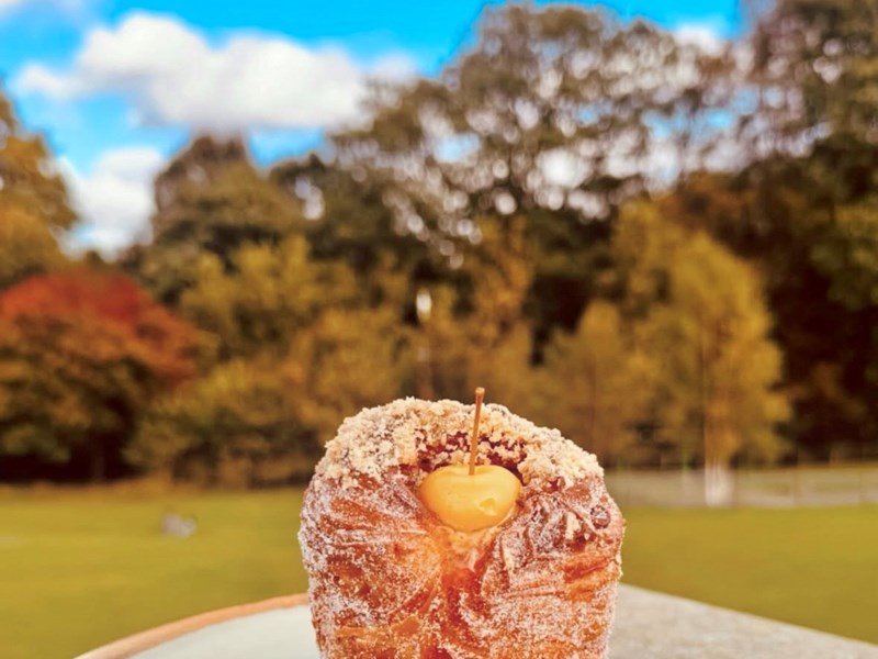 A cruffin on a plate against the backdrop of the park during autumn