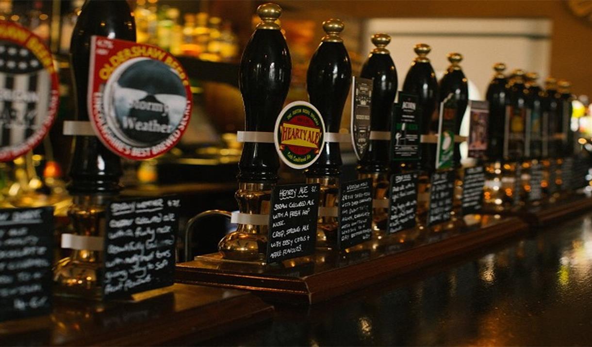 A row of beer taps on a traditional pub bar.