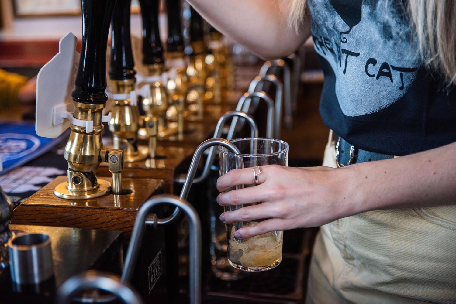 A member of staff, at The Fat Cat, pulling a pint.