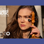 A headshot of a person holding a violin.