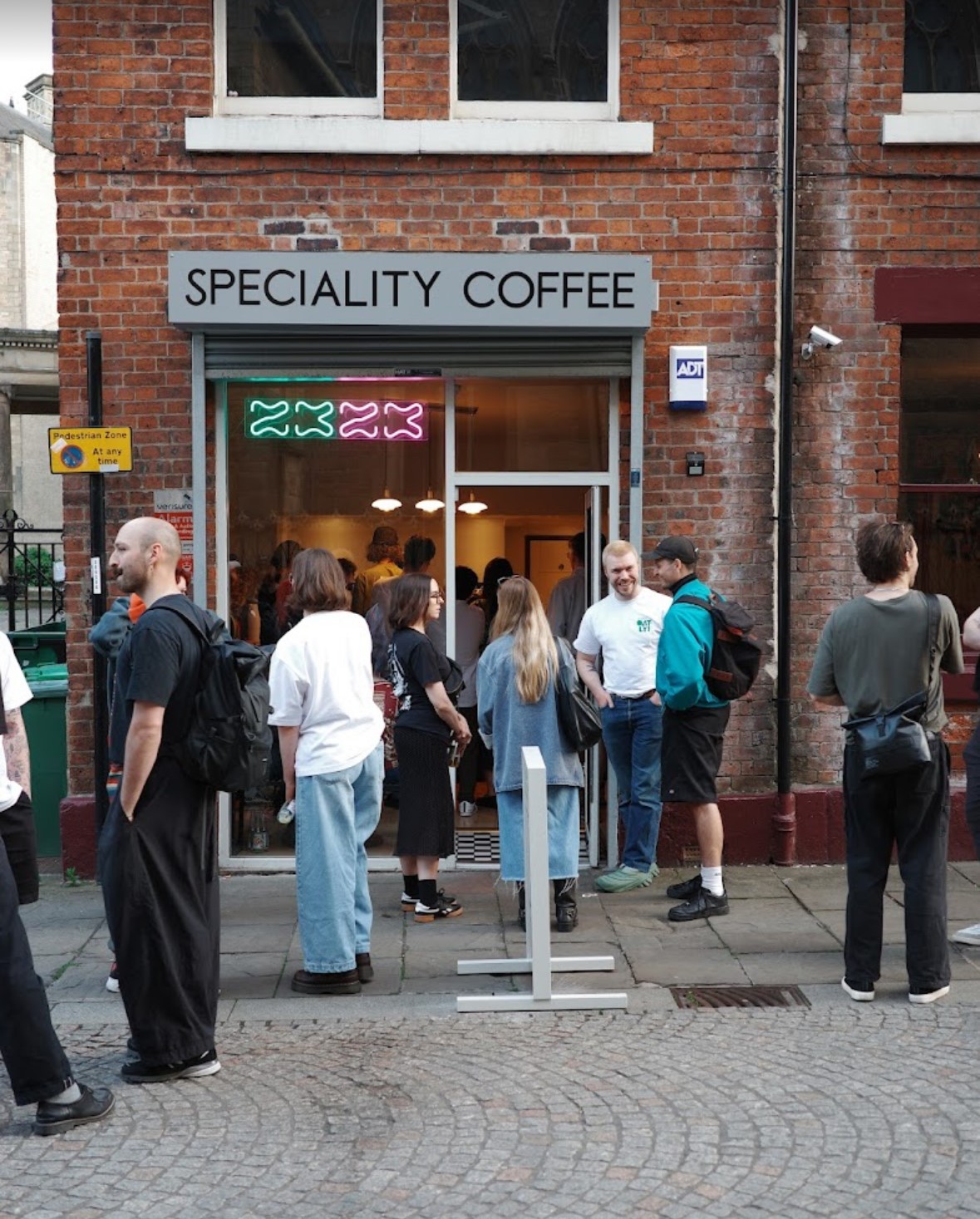 exterior of 2323 coffee shop with people stood on the cobbled street outside 