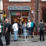 exterior of 2323 coffee shop with people stood on the cobbled street outside 