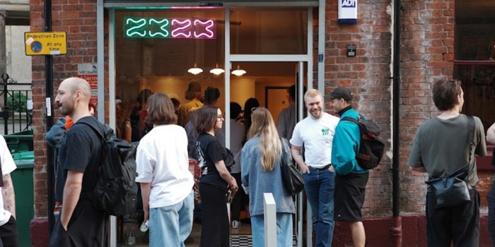 exterior of 2323 coffee shop with people stood on the cobbled street outside 