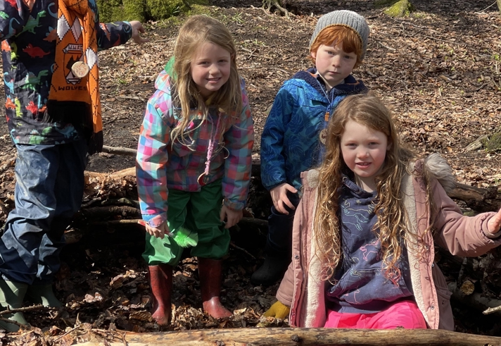 A group of children playing in a wooded area.