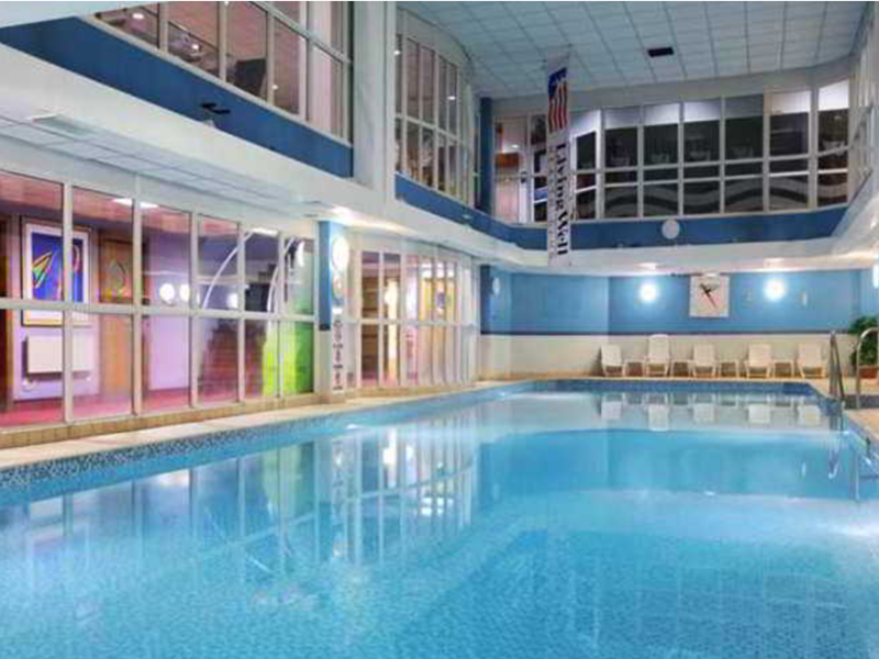 Large swimming pool with ambient lighting inside a leisure centre.