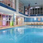 Large swimming pool with ambient lighting inside a leisure centre.