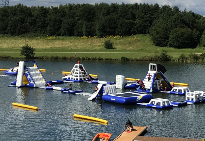 A variety of inflatable obstacles are floating on a lake.