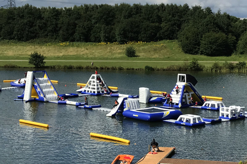 A variety of inflatable obstacles are floating on a lake. 