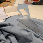 A group of people sat round a table cutting patterns from cloth.