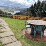 A table and chairs in a garden, overlooking a valley.