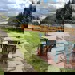 A table and chairs in a garden, overlooking a valley.