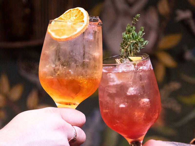 Two cocktails being held.