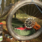 A tarpaulin and a bike wheel used to make a shelter in a wood.