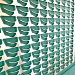 Close-up of a blue decorative panel with a silver metallic overlay featuring elongated spoon-like cut-out shapes arranged in a symmetrical pattern.