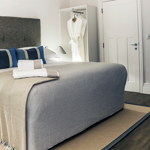 Beautiful double bed with soft furnishings in light, neutral colors and decorative cushions.