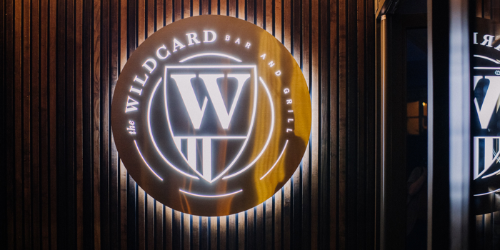 The Wildcard Bar & Grill's logo, lit up, on a wall.