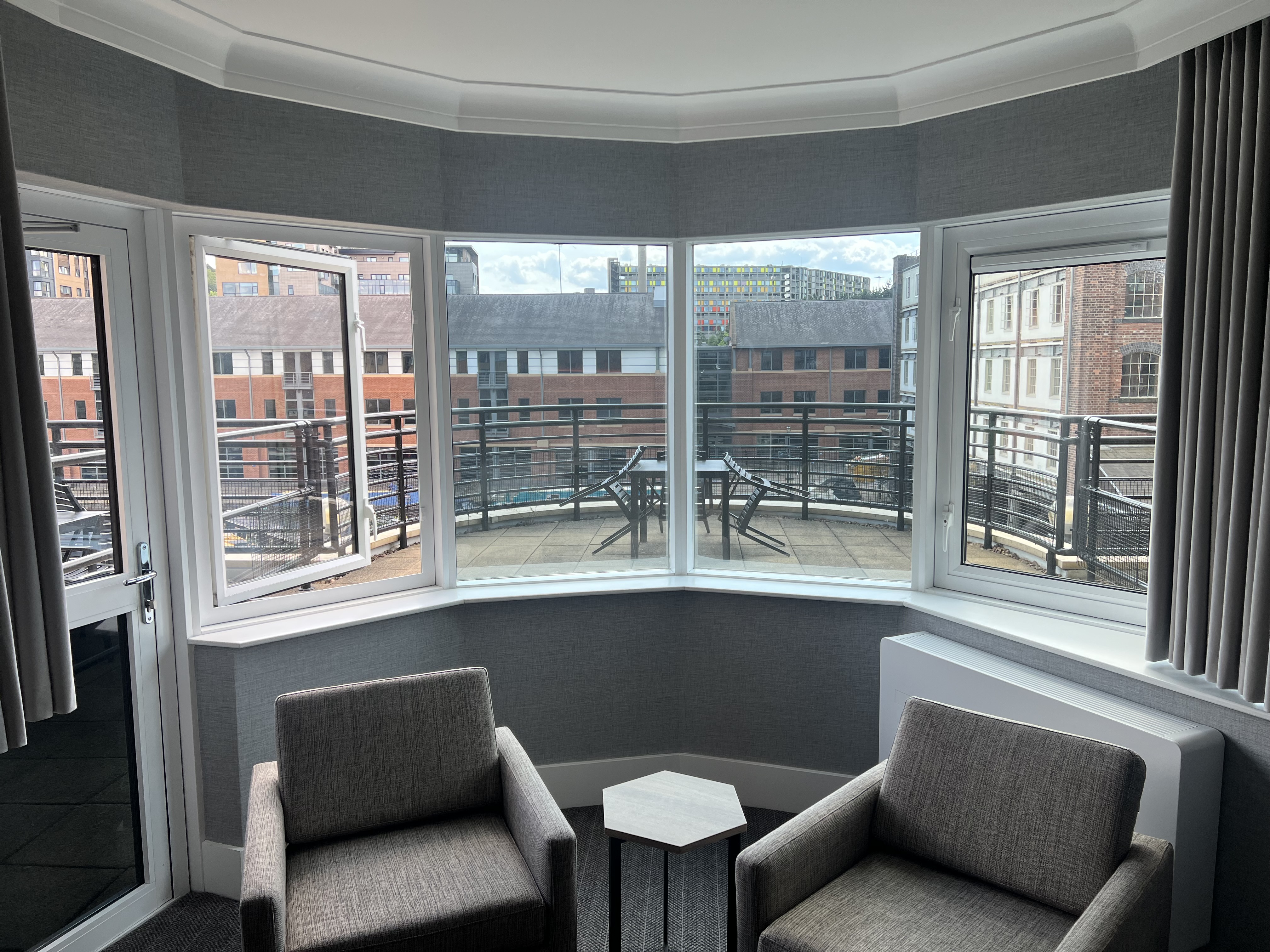 Bedroom with two cozy chairs and a window overlooking the balcony.