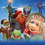 Colorful promotional artwork for Disney Concerts featuring characters from The Muppet Christmas Carol. Kermit the Frog appears twice, dressed in Victorian-style clothing, one holding a walking stick and another wearing a top hat. Gonzo is perched on a lamppost wrapped in festive greenery, wearing a striped scarf and red coat. The background shows a snowy street scene with old-fashioned buildings under a bright blue sky.