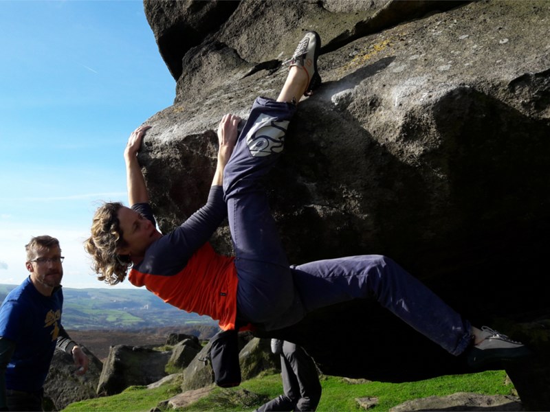 Two people climbing a boulder.