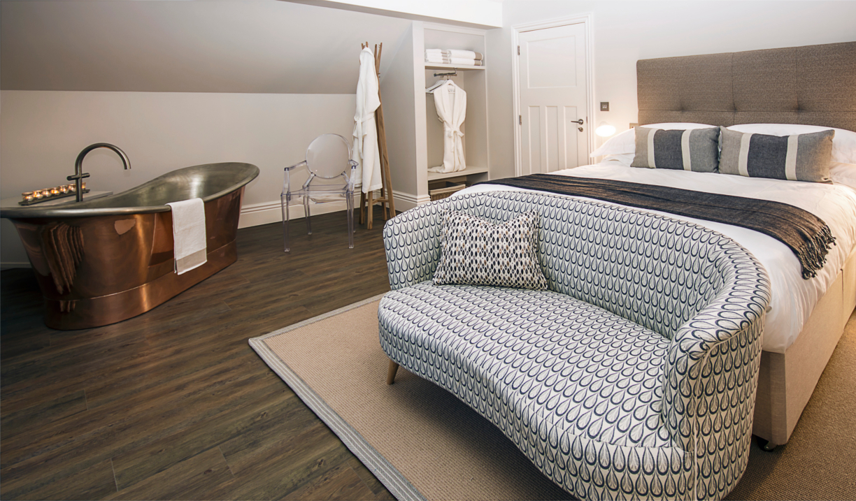A lavish room at Brocco On The Park, with a double bed, a sofa and a free-standing copper bath.