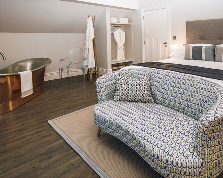 A lavish room at Brocco On The Park, with a double bed, a sofa and a free-standing copper bath.