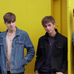 The Sherlocks pose against a yellow wall.