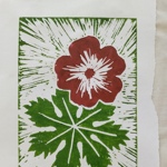 A linocut-style print featuring a bold red flower with a white starburst centre above a large green leaf. The background is filled with radiating green lines that create a sense of movement around the central shapes.