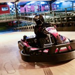 A person driving a go-cart on an indoor track.