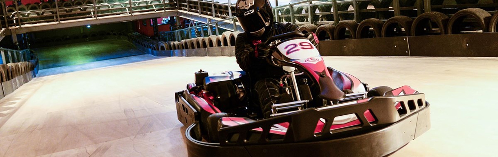 A person driving a go-cart on an indoor track.