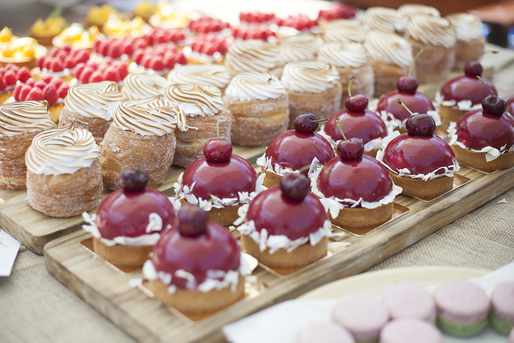 Rows of small cakes and pastries are laid out on display on a stall.