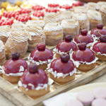 Rows of small cakes and pastries are laid out on display on a stall.