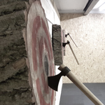 Three wooden targets on a wall, each with a throwing axe in the bullseye.