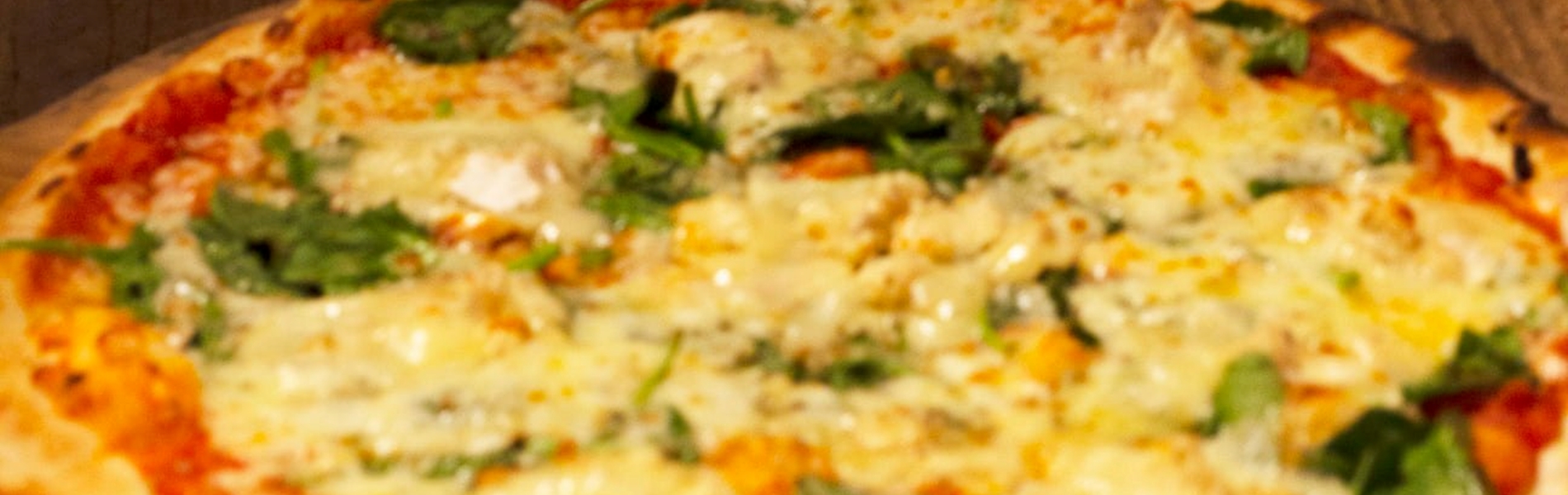 Pizzas fresh out the oven about to be cut up into slices.