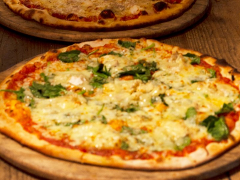 Pizzas fresh out the oven about to be cut up into slices.