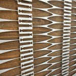 Close-up of a decorative panel featuring alternating wooden and metal elements in a repeating geometric pattern with elongated shapes and cut-out details