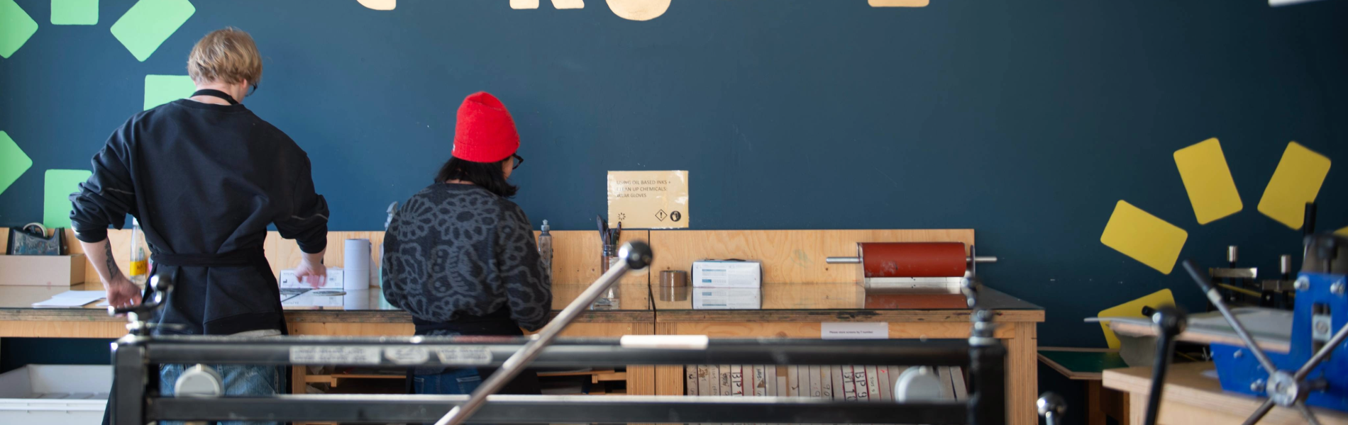 Two people standing, working at a bench in a print studio.