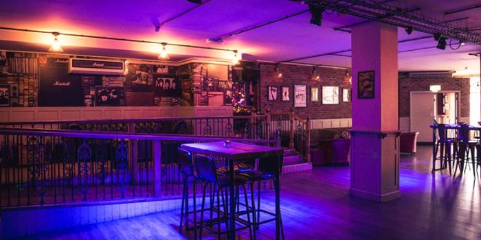 The dance floor and bar at Maida Vale, lit by purple lighting.