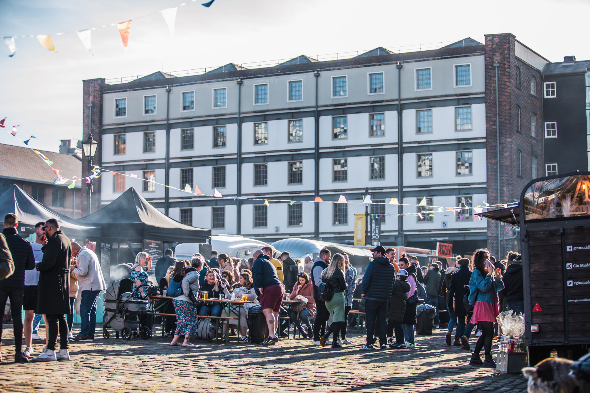 Victoria Warehouse building with market stalls laid out along the cobbles in front 