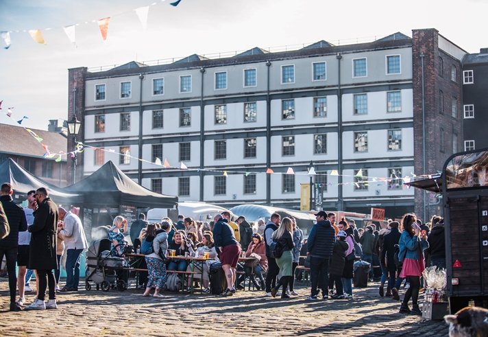 Victoria Warehouse building with market stalls laid out along the cobbles in front