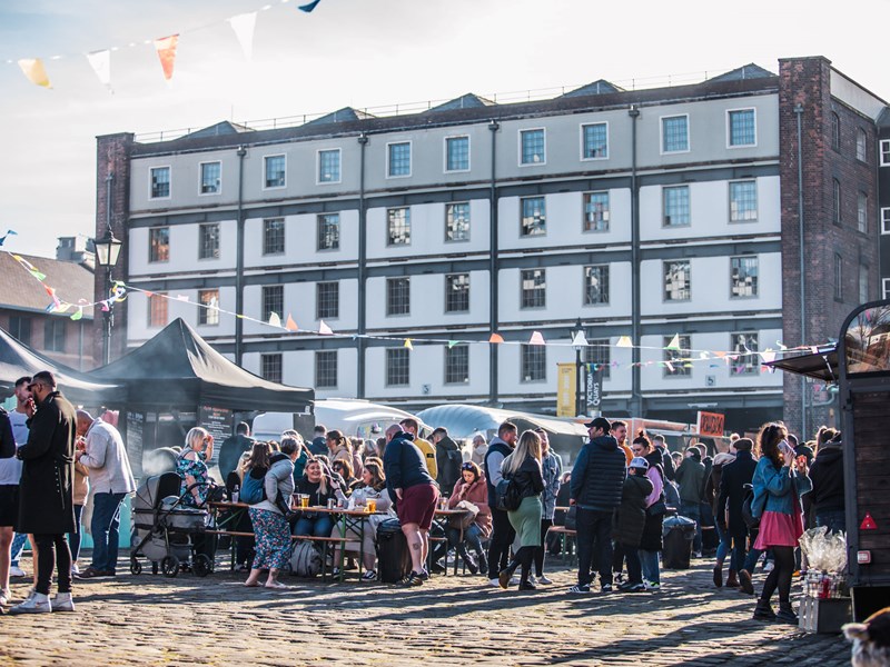 Victoria Warehouse building with market stalls laid out along the cobbles in front