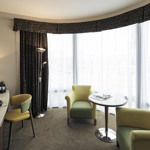 Spacious sitting area in a junior suite featuring a coffee table, armchair, and large windows with natural light