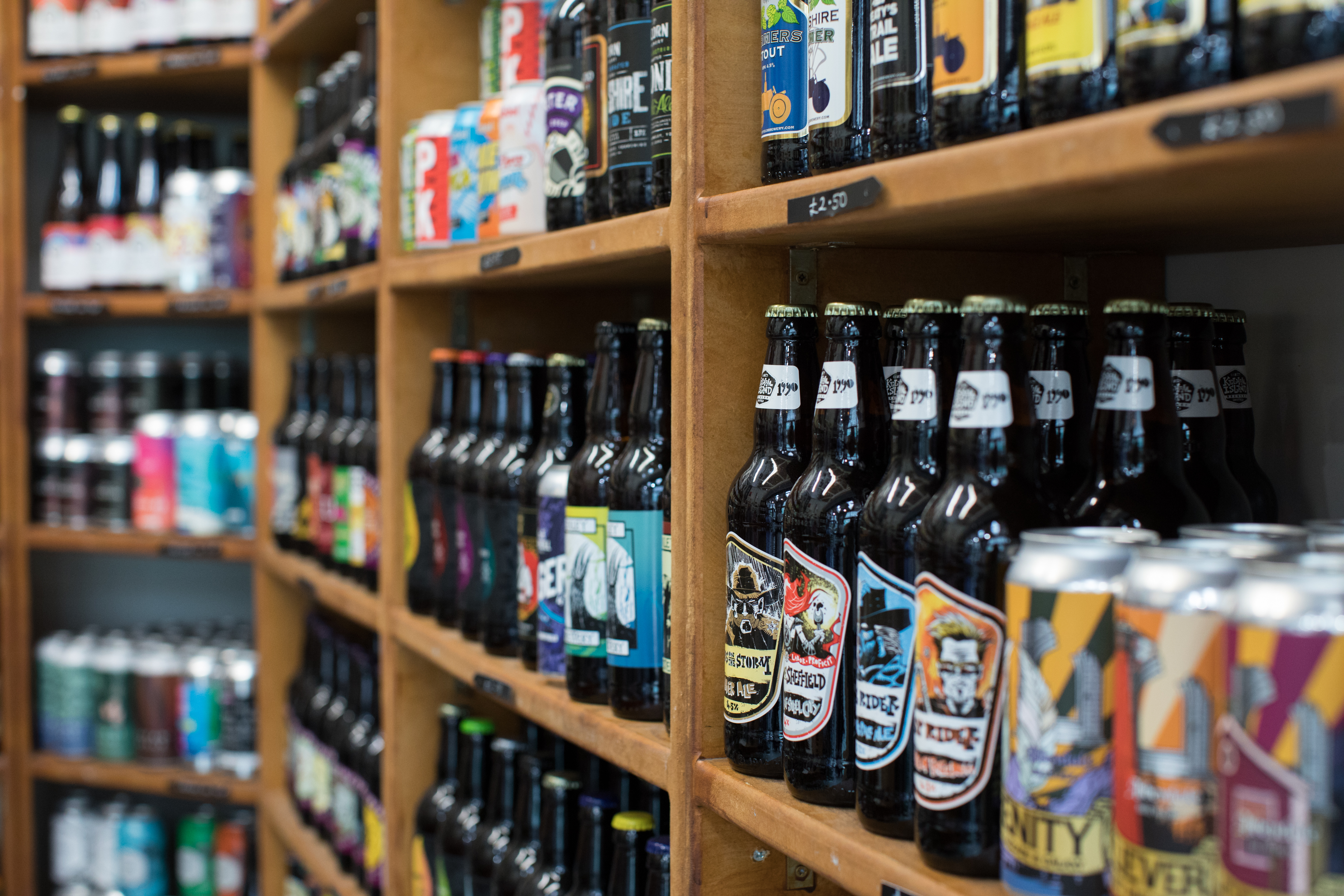 A store shelf filled with a wide variety of beers, including colorful cans and neatly arranged bottles, suggesting a large selection.
