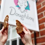 A cookie being broken in two, in front of the Doughboy Cookie Shop sign.