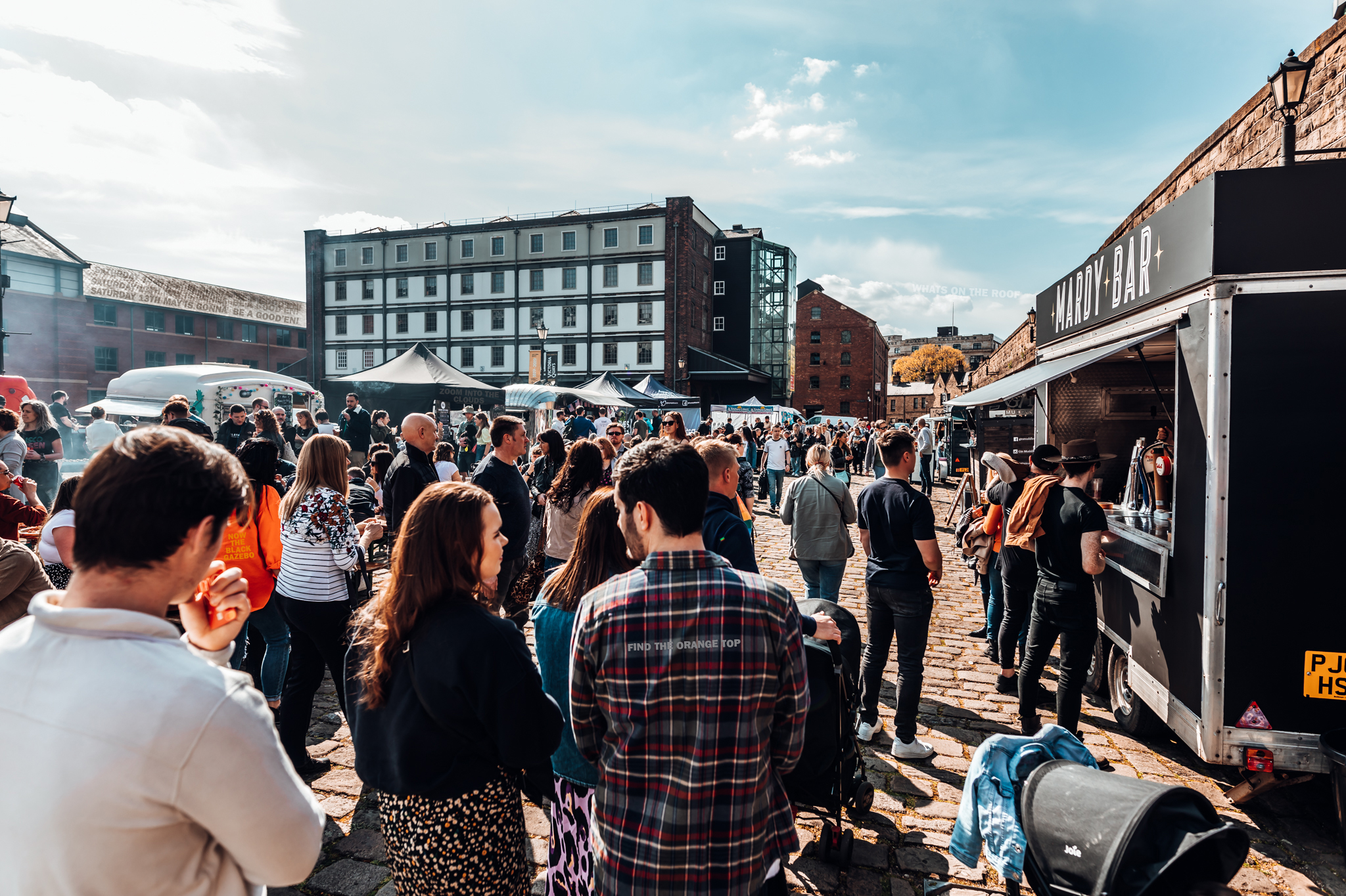 Walking behind a crowd of people as they peruse stalls at Quayside Market on a sunny day 