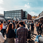 Walking behind a crowd of people as they peruse stalls at Quayside Market on a sunny day 