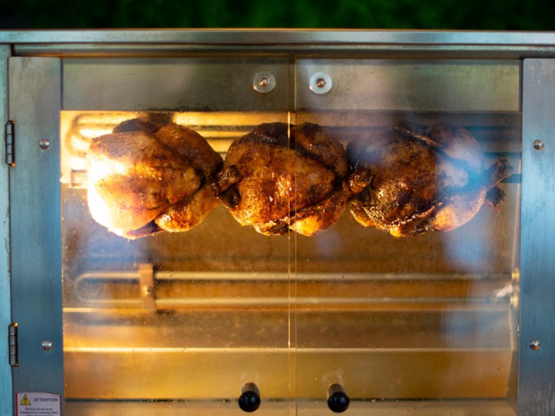 Three chickens in a rotisserie oven at Chop Shop Bar & Grill.