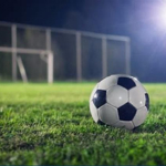 A black and white football sitting on a grass pitch.